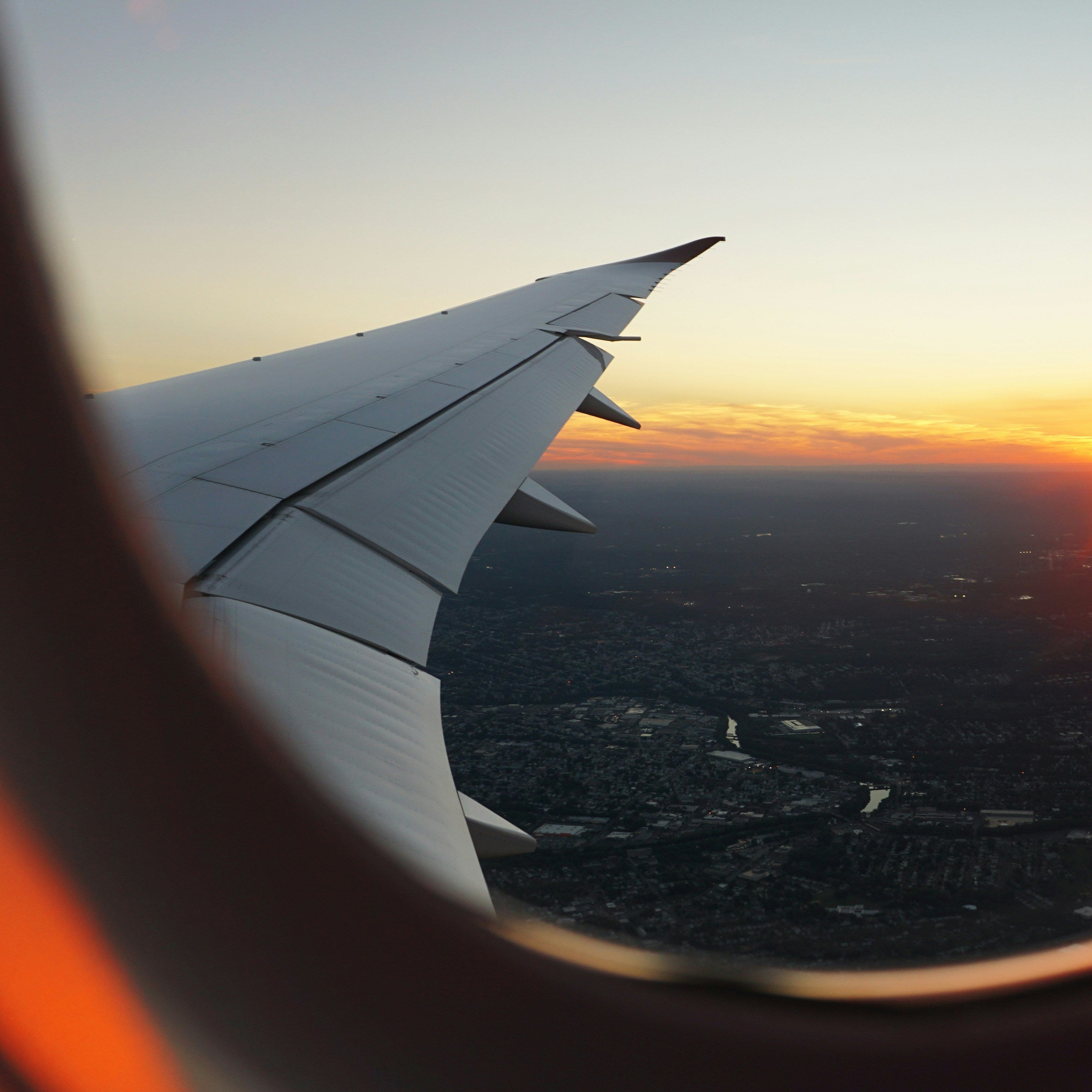 Airplane wing view from an airplane window during sunset.
