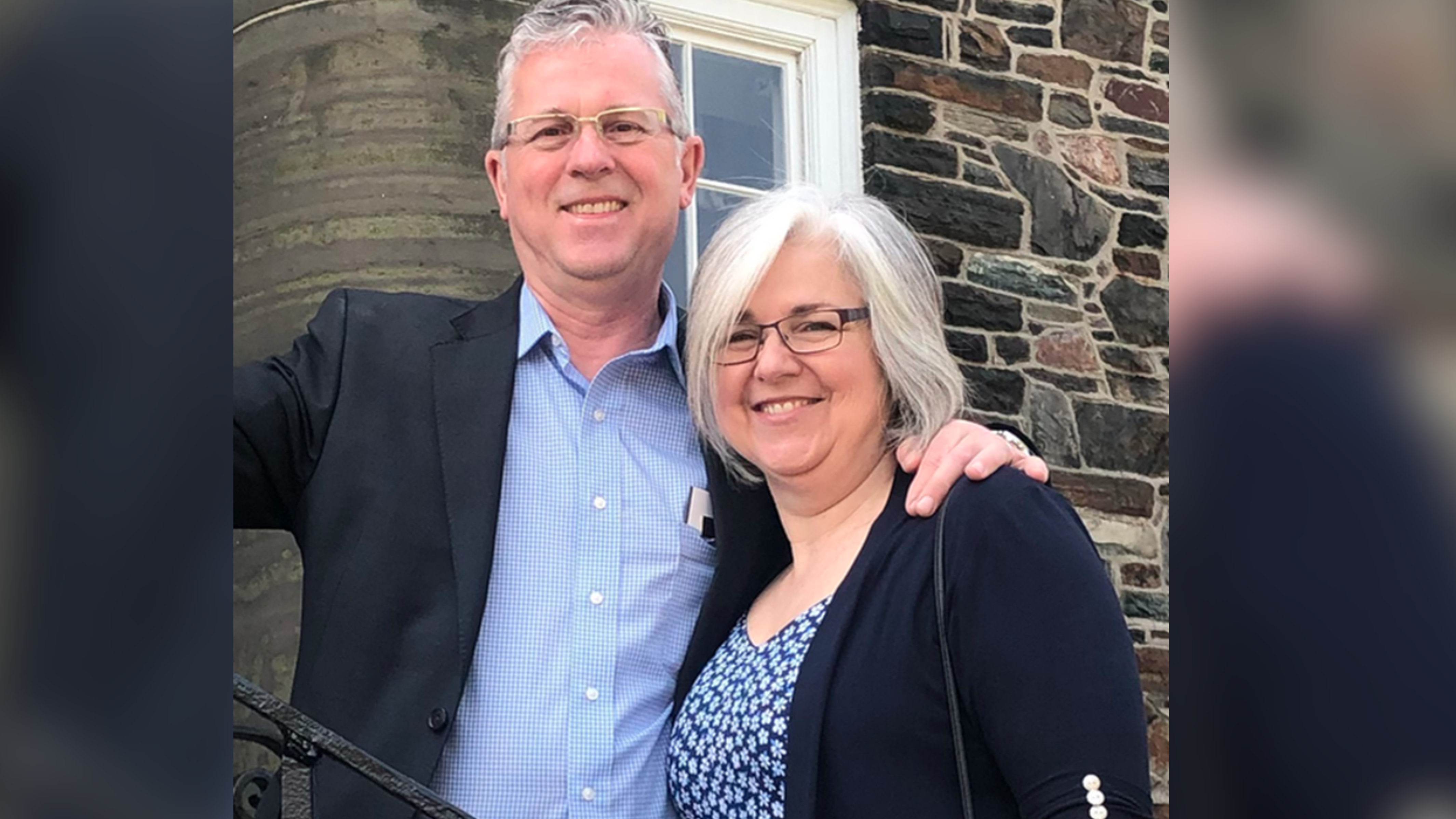 photo of couple in front of window and brick wall