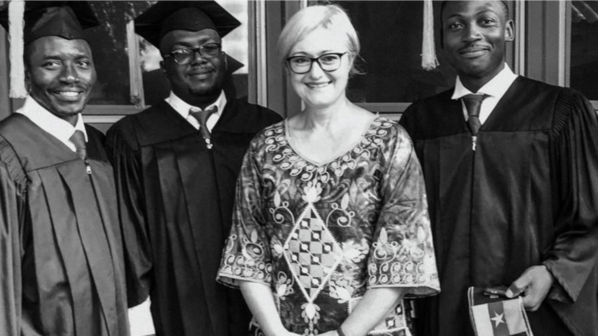black and white photo of GW and three graduates in robes smiling at camera