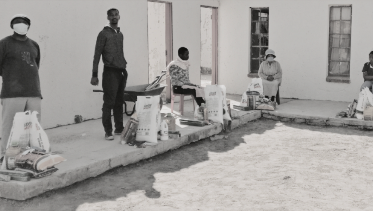 black and white photo of five individuals on a construction site working on an unfinished house