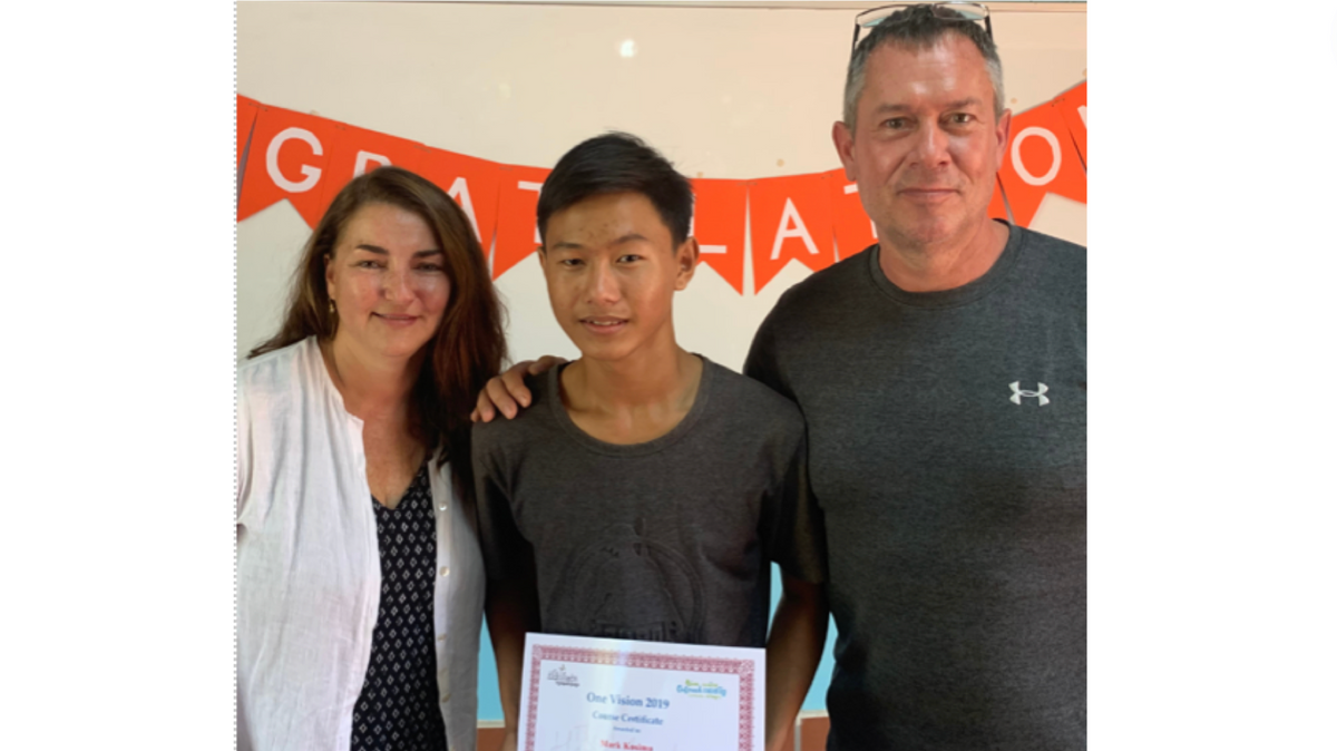 photo of couple and young boy holding a diploma certificate smiling at camera.
