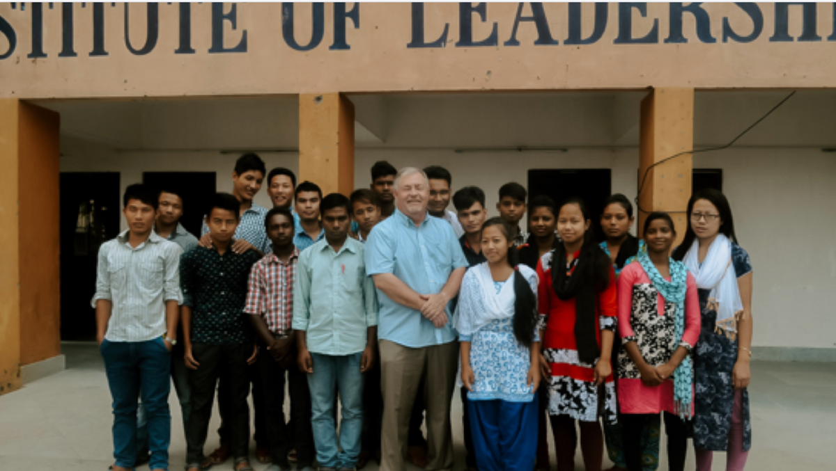 group photo of man and various young adult men and woman taking a group photo outside a building - institute of leadership