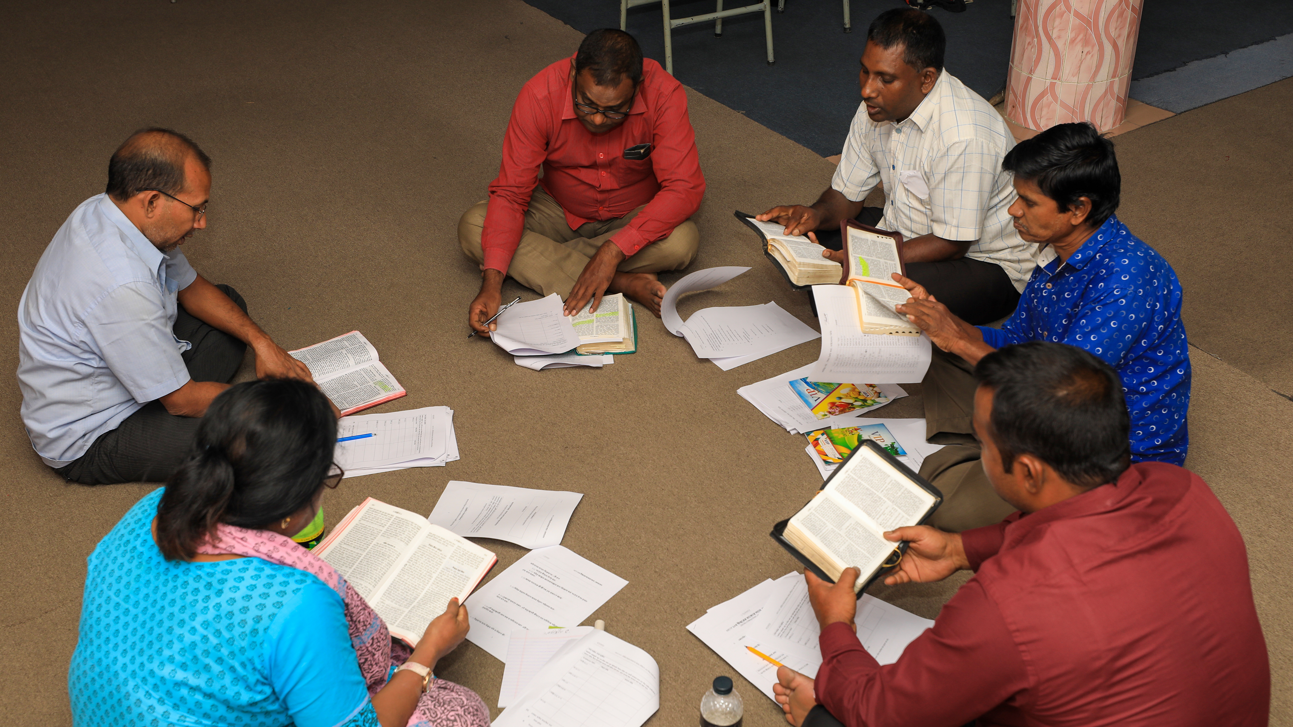 group of people reading bibles on the ground